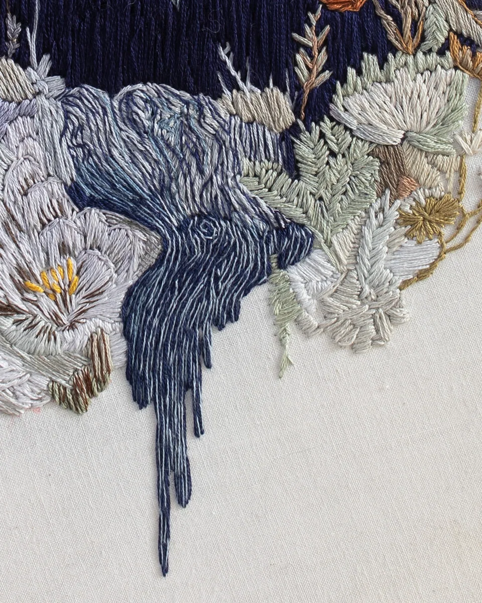 Close detail of the raven and pale floral embroidery