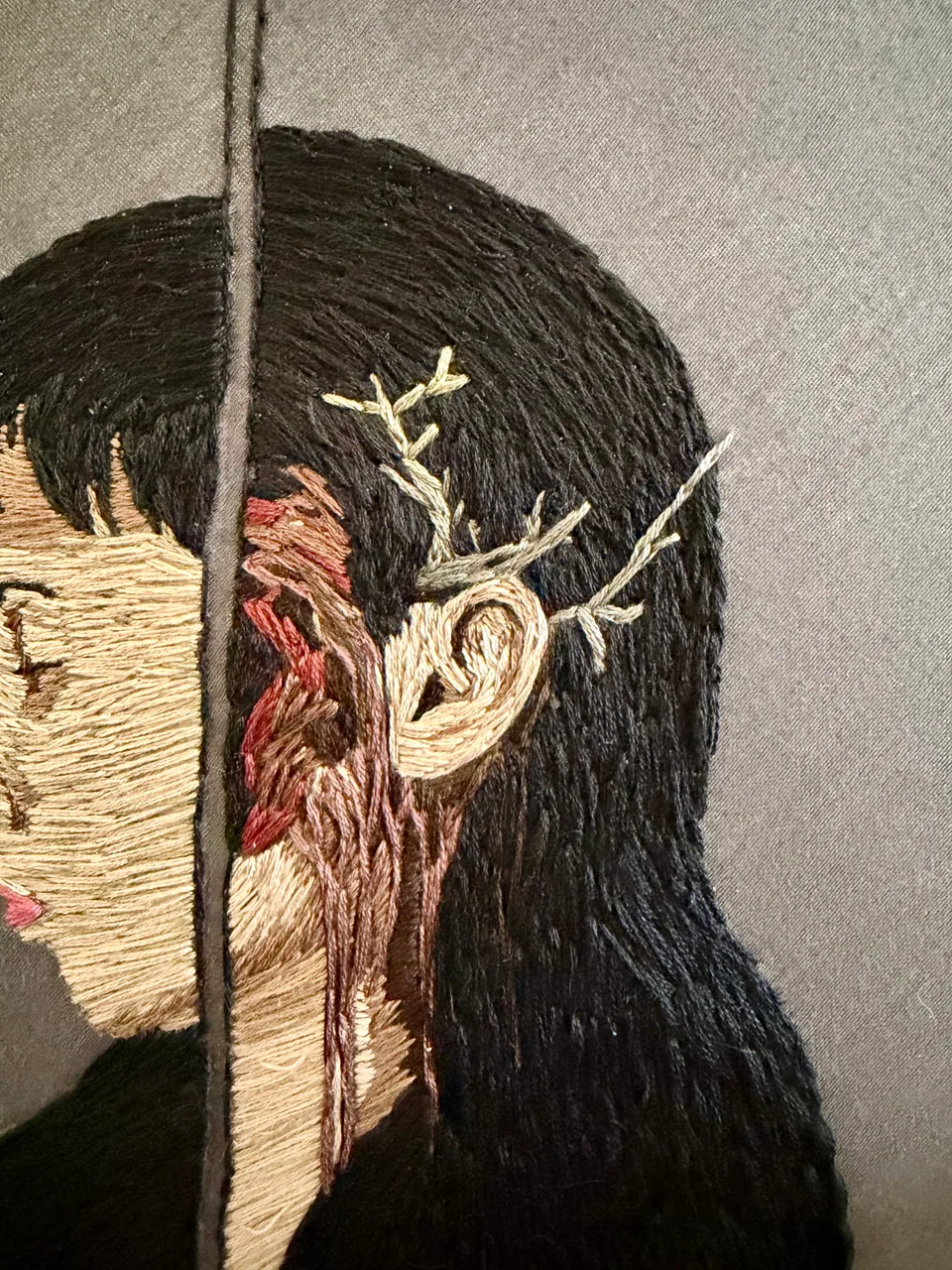 Close detail of branching stitches beside the portrait's ear