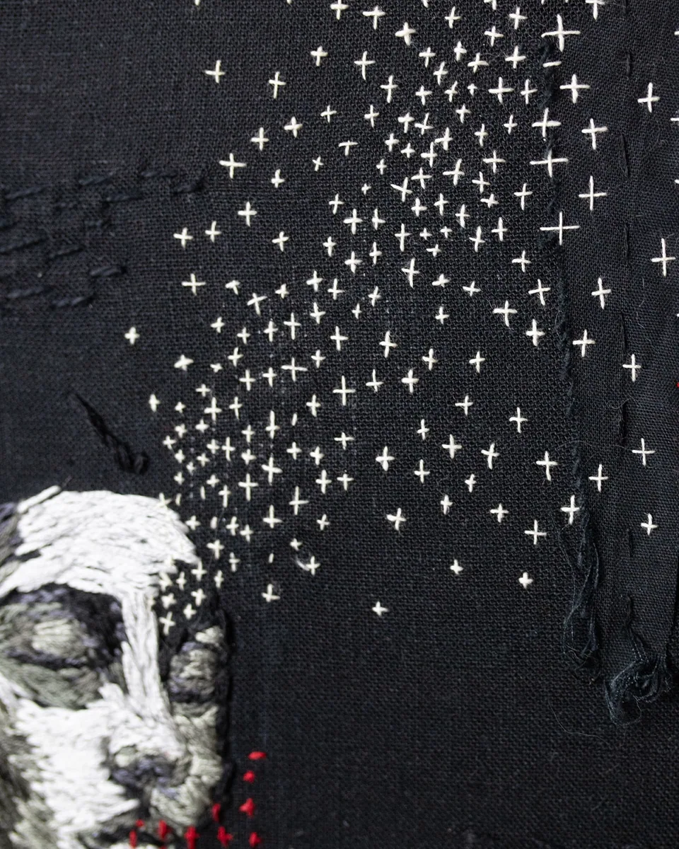Close detail of the embroidered figure and white stitched stars