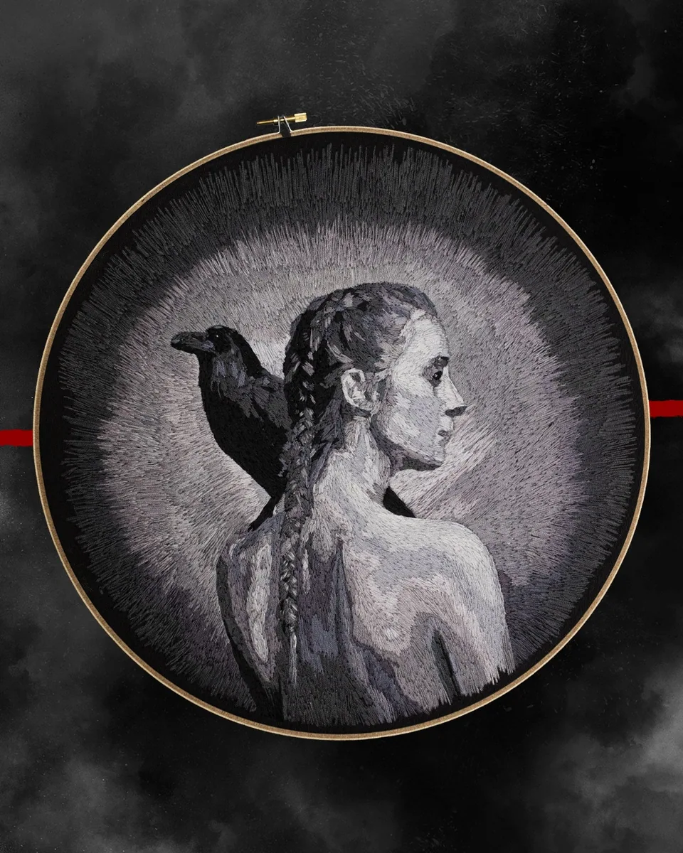 Grayscale embroidered portrait of a woman with a raven